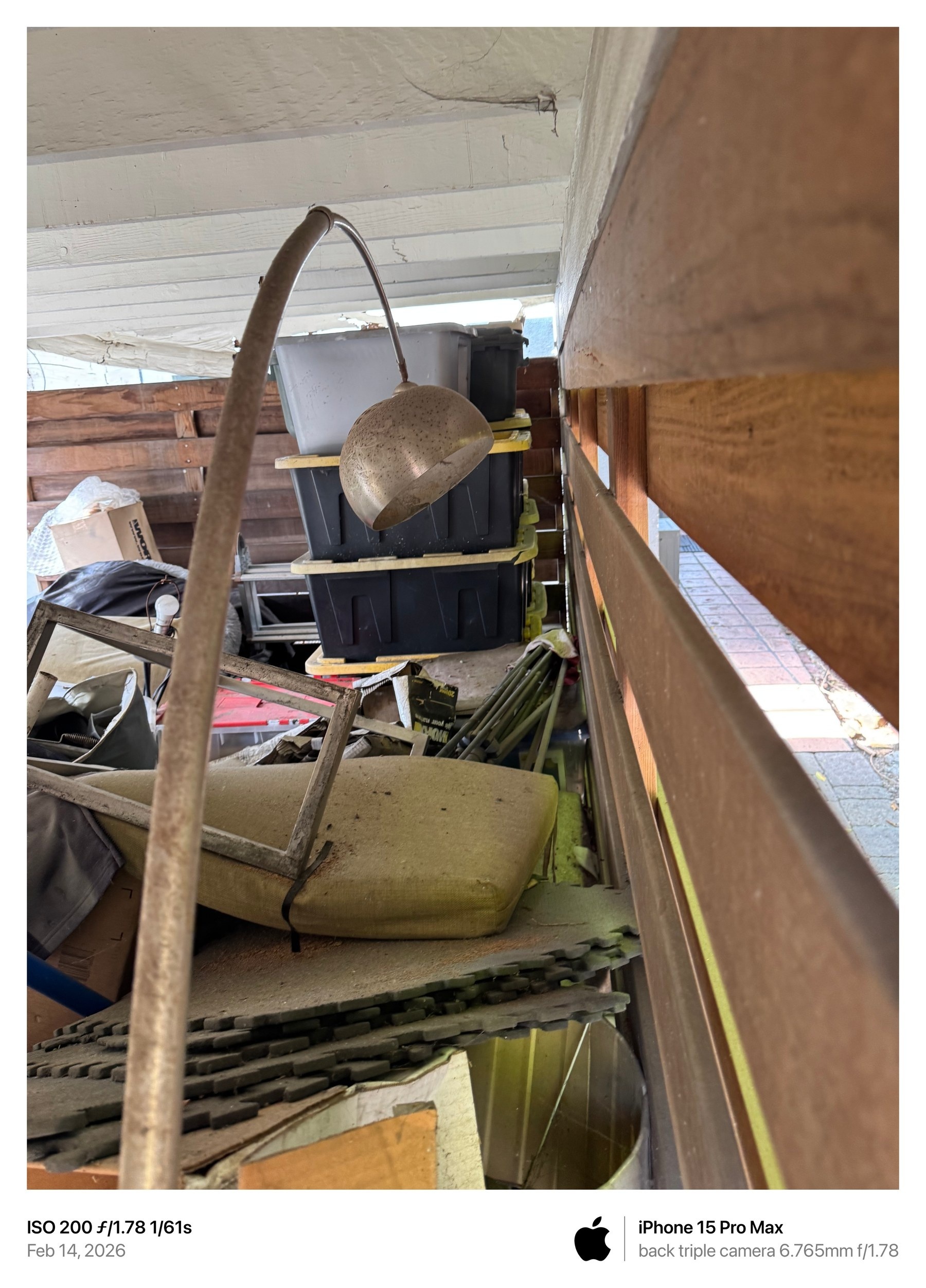 February 14, 2026 photograph showing a hanging light fixture and stacked materials in the narrow exterior area